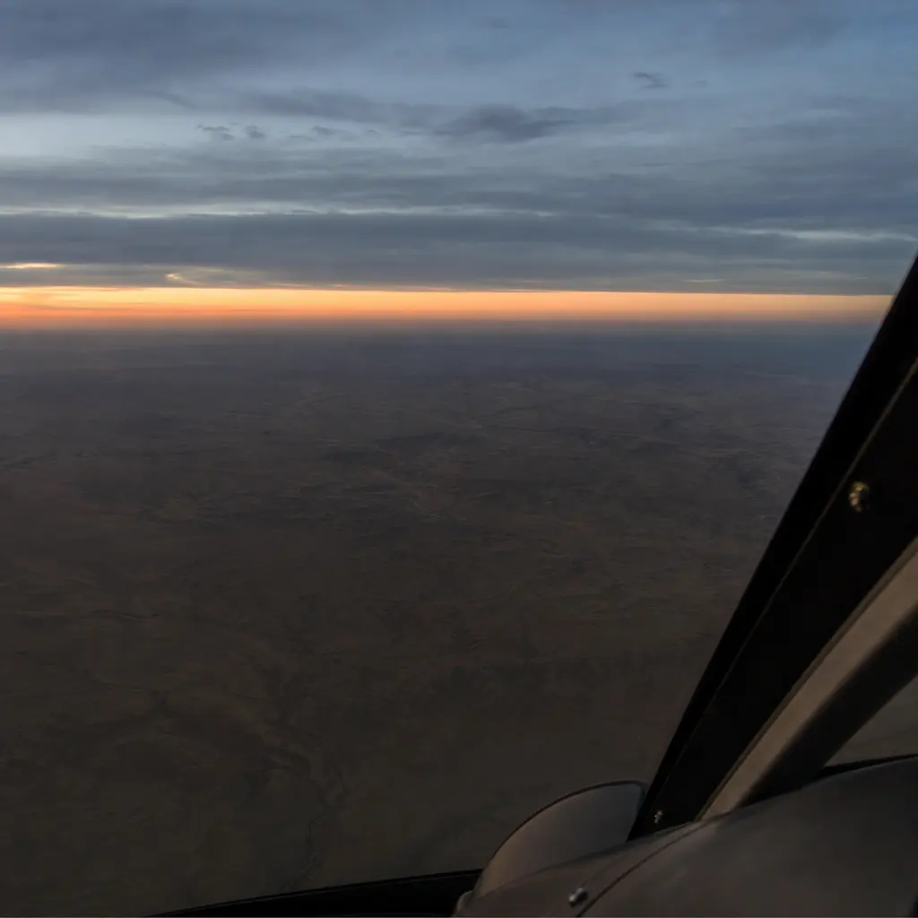Looking down over featureless desert terrain at dusk with no roads, buildings or landmarks in view