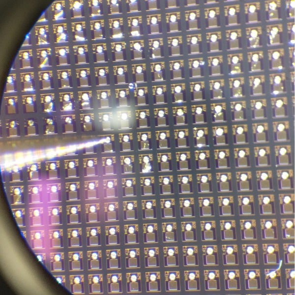 A VCSEL wafer seen through a microscope, showing hundreds of identical dies in a regular grid